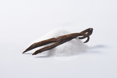 Heap of white granulated sugar and two dried vanilla beansの写真素材