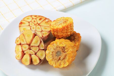 Corn on the cob and halved garlicの写真素材