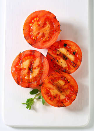 Grilled tomatoes on white cutting boardの写真素材