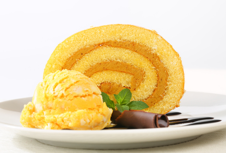 Slice of Swiss roll with yellow ice cream and chocolate sauceの写真素材