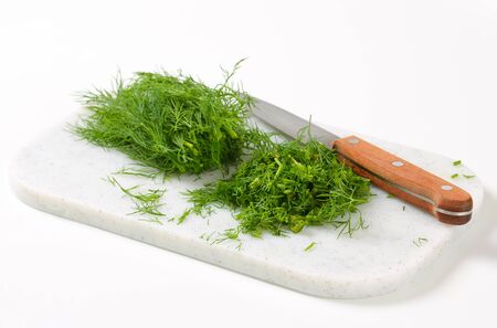 Sprigs of fresh dill weed on cutting boardの写真素材