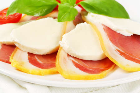 Sliced prosciutto crudo and mozzarella with fresh basil and tomatoesの写真素材