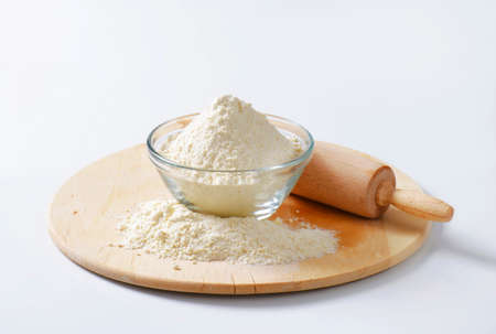 Bowl of flour and rolling pin on a wooden board