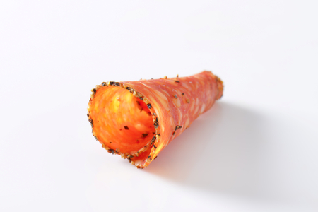 Single slice of black pepper-coated salami speckled with pieces of Comte cheeseの写真素材