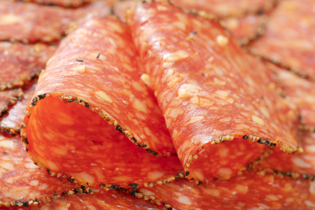 Thin slices of black pepper-coated salami speckled with pieces of Comte cheeseの写真素材