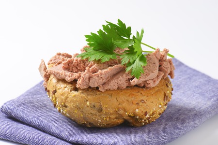 fresh bun with pate and parsley on blue tablecloth
