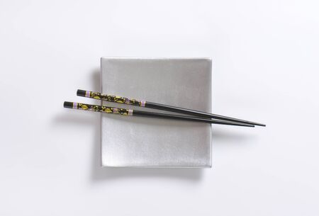 pair of black chopsticks on silver plate