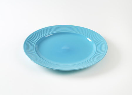 Blue glazed dinner plate with embossed concentric rings on the edgeの写真素材