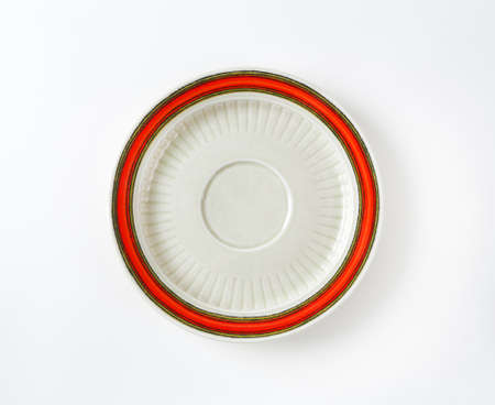 white saucer with red rim on white backgroundの写真素材