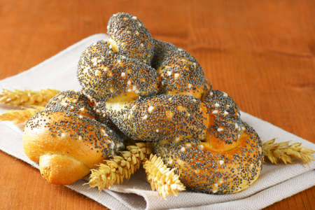 Braided bread rolls topped with poppy seeds and saltの写真素材