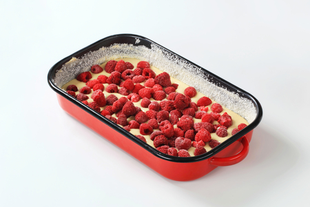 raw cake batter with frozen raspberries in baking tray ready to be bakedの写真素材