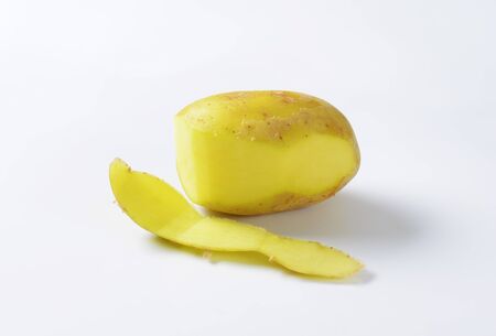 Single fresh potato, partially peeledの写真素材
