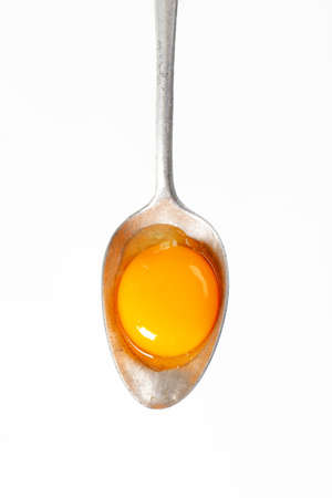 Raw egg yolk on a spoonの写真素材
