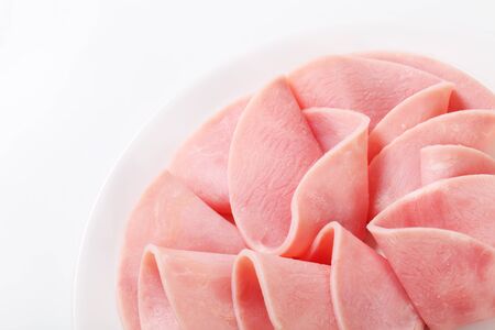 Thin slices of ham on white plateの写真素材