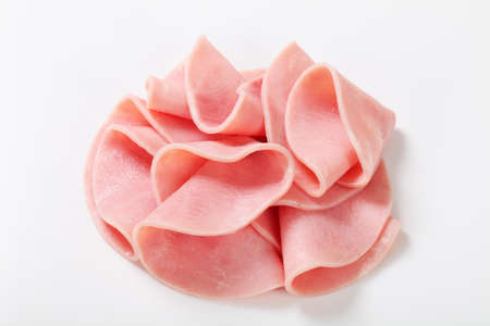Thin slices of ham on white backgroundの写真素材
