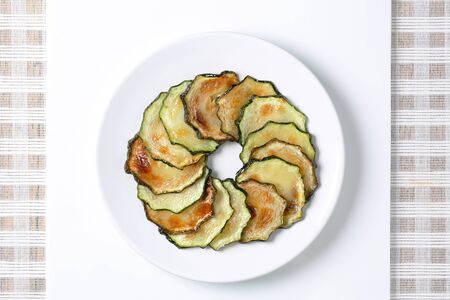 circle of thin slices of roasted zucchini on a white plateの写真素材