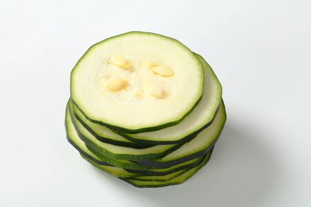 stack of thin slices of fresh zucchini on a white backgroundの写真素材