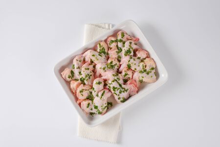 raw chicken wings with chopped parsley in white ceramic baking dishの写真素材