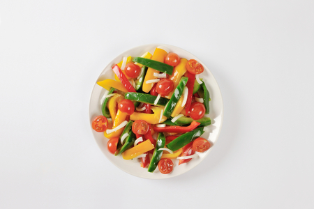 Plate of fresh bell pepper strips and halved cherry tomatoesの写真素材