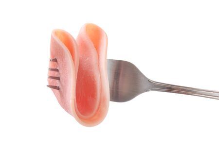 slice of ham on a fork isolated on whiteの写真素材