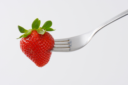 whole fresh strawberry on forkの写真素材