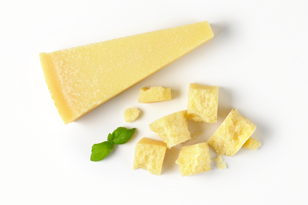 wedge and pieces of fresh parmesan cheese on white backgroundの写真素材