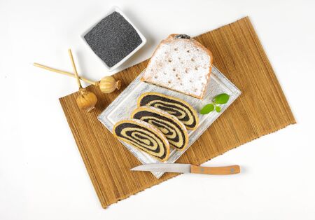 bowl of poppy seeds and sliced poppy seed roll on wooden cutting boardの写真素材