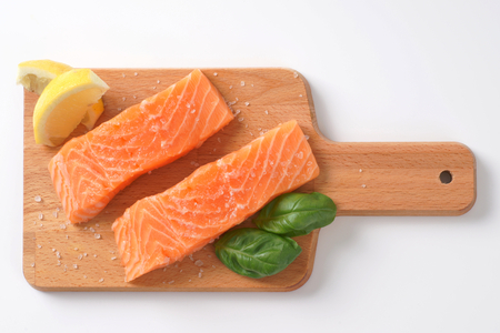 two salted salmon fillets on wooden cutting boardの写真素材