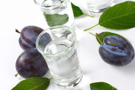 Plum brandy (slivovitz) in shot glasses and fresh damson plumsの写真素材