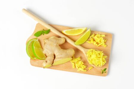 whole and grated fresh ginger with lime and lemon on wooden cutting board