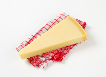 Wedge of Parmesan cheese on checked tea towelの写真素材