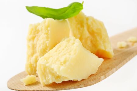 Pieces of Parmesan cheese on wooden spatula