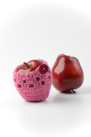 two red apples, one in crochet apple cozyの写真素材