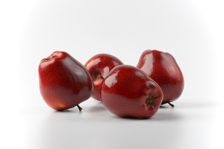 four glossy red apples on off-white backgroundの写真素材