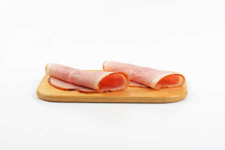 two ham slices rolled up on wooden cutting boardの写真素材