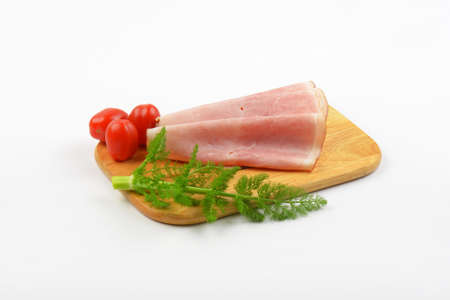 ham slices with dill an cherry tomatoes on wooden cutting board