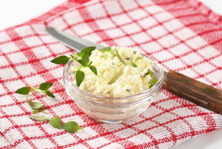 close up of homemade cheese spread with herbs in glass bowlの写真素材