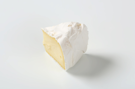 slice of white rind cheese on white backgroundの写真素材