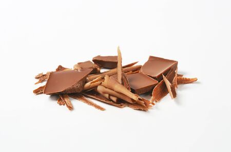 Milk chocolate shavings and pieces on white backgroundの写真素材
