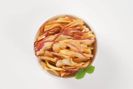 bowl of dried apple chips on white backgroundの写真素材