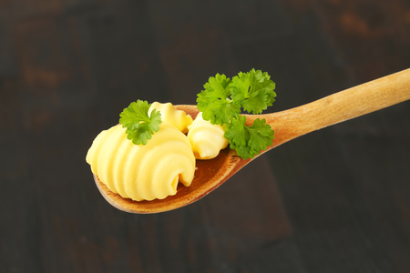 butter curls and fresh parsley on wooden spoonの写真素材