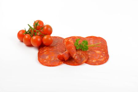 slices of chorizo salami and cherry tomatoes on white backgroundの写真素材