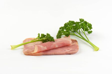 slices of pork ham with parsley on white backgroundの写真素材