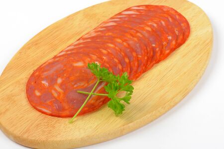 slices of chorizo salami on oval wooden cutting board - close upの写真素材