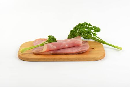sliced pork ham with parsley on wooden cutting boardの写真素材