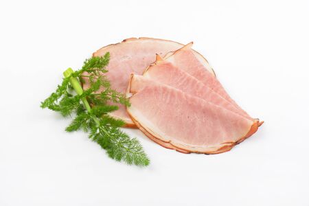 slices of ham and twig of fresh dill on white backgroundの写真素材