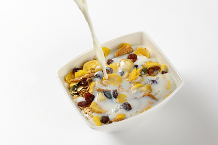 milk pouring into bowl of breakfast cerealsの写真素材
