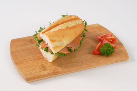French bread sandwich with smoked salmon on wooden cutting boardの写真素材