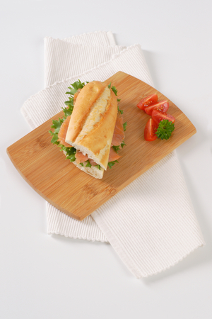 French bread sandwich with smoked salmon on wooden cutting boardの写真素材