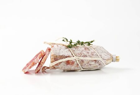 sliced dry cured sausage and thyme on white backgroundの写真素材